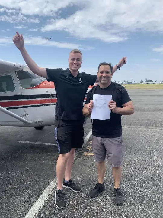 Student pilot celebrating with friends and family after passing the private pilot checkride